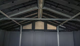 Interior de un cobertizo de jardín de plástico gris oscuro con vigas metálicas y tres rejillas de ventilación