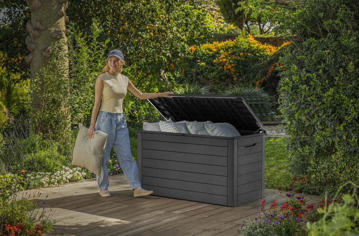 Baul Keter Ontario abierto en un jardin, guardando cojines de exterior